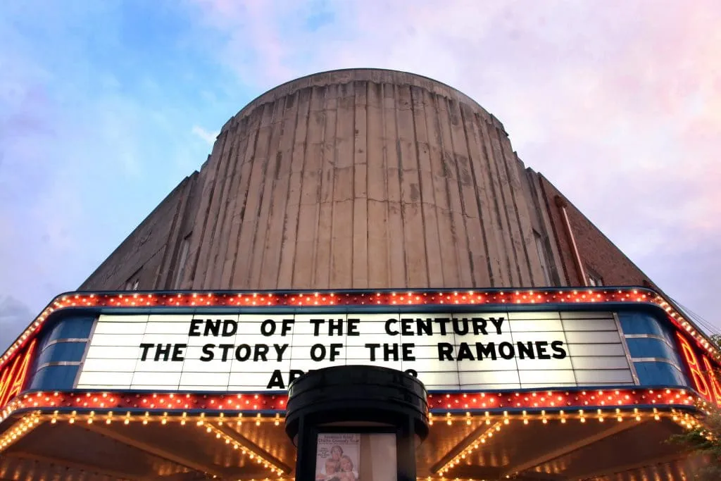 Dramatic bronze hand sculpture holding violin against cloudy sky backdrop