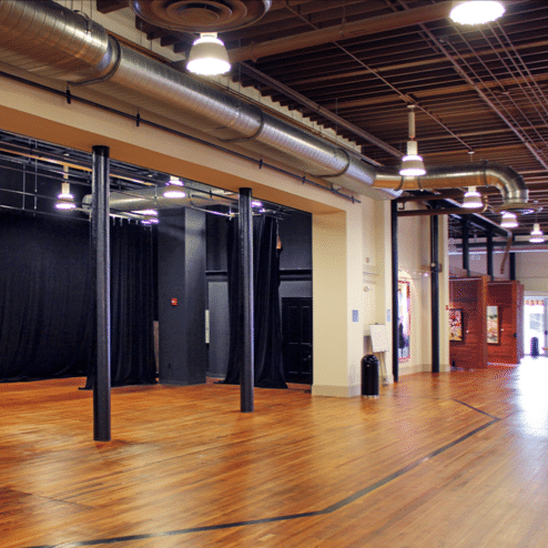 Black box theatre hallway with wood floors and tall ceilings.