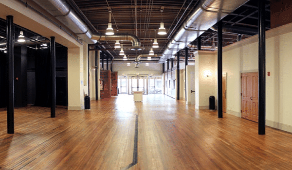 Tall gallery hallway with wood floors and overhead lights. 