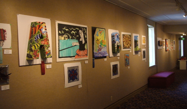 Row of art of different mediums hung up on walls.