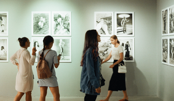 Women walking through gallery looking at art on walls.