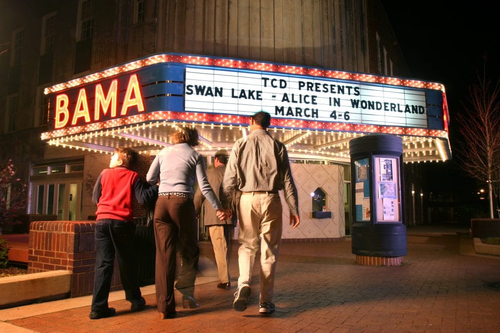 Bama theatre marquee lit up at night with people walking toward theatre entrance.